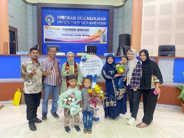 Fitriani menyerahkan sertifikatnya kepada suaminya, Gazali Rifai, usai pengukuhan disaksikan para penguji di Kampus UNM.